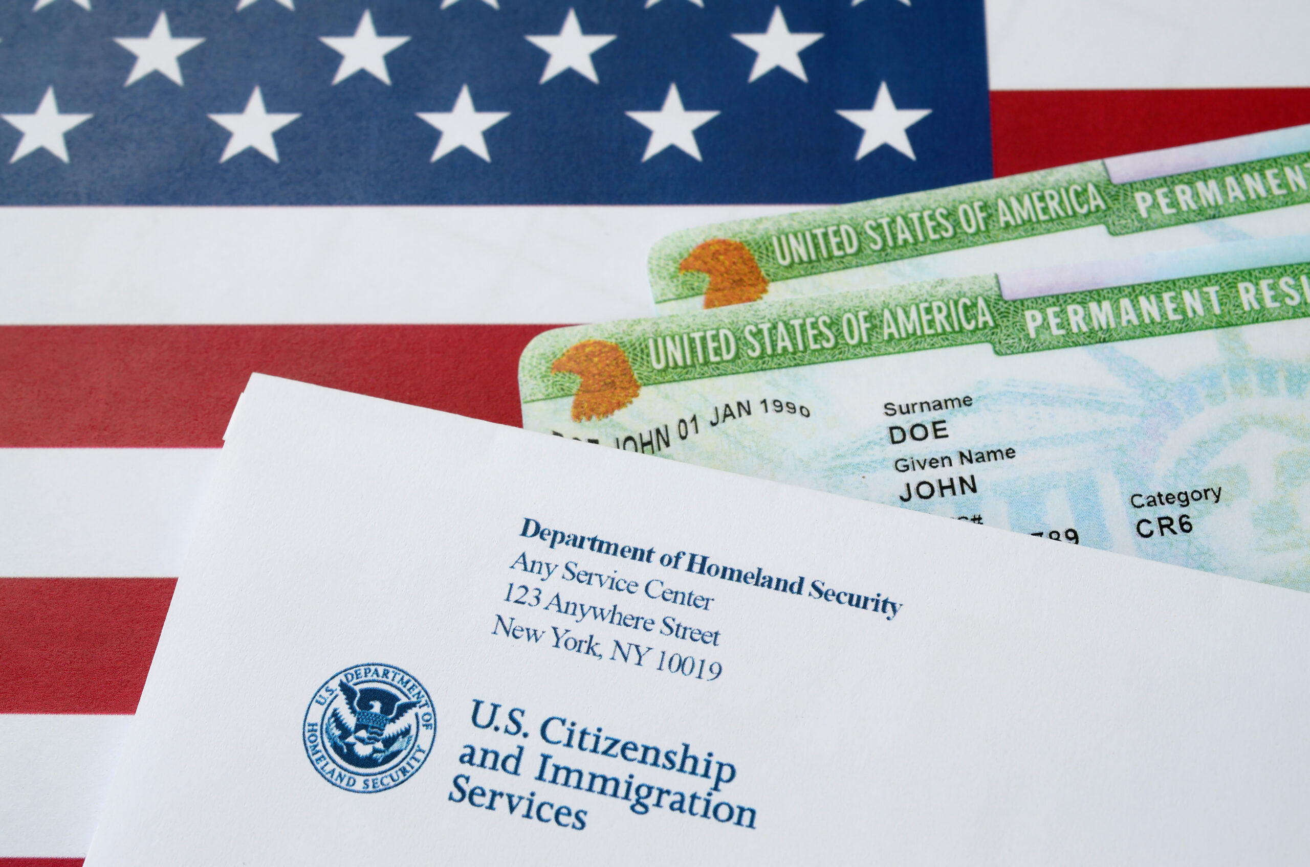 United States Permanent resident green cards from dv-lottery lies on United States flag with envelope from Department of Homeland Security